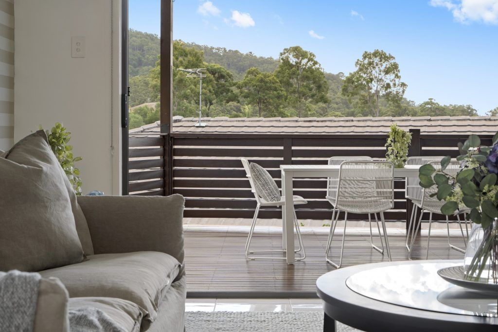 A living room with a couch , table , chairs and a view of a balcony.