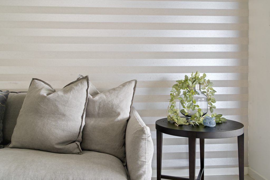 A living room with a couch and a table with a plant on it.