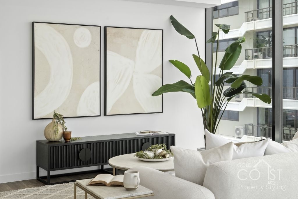 A living room with a couch , table , and two paintings on the wall.