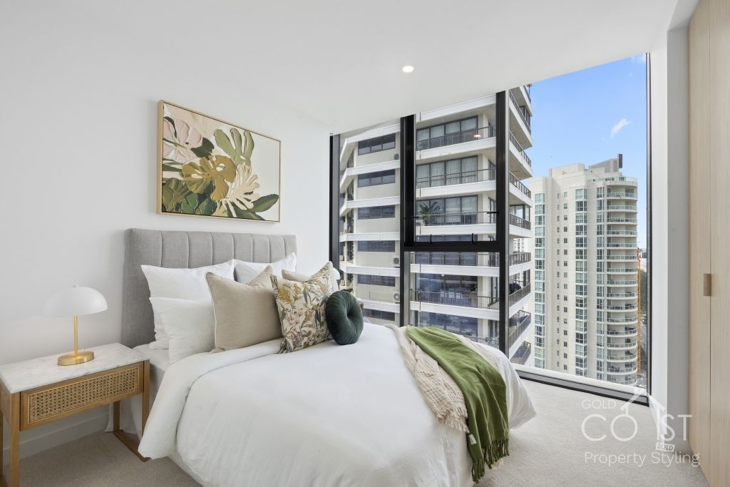 A bedroom with a large bed and a large window with a view of a city.