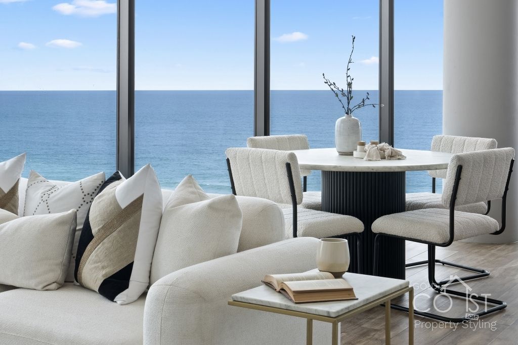 A living room with a couch and a table with a view of the ocean.