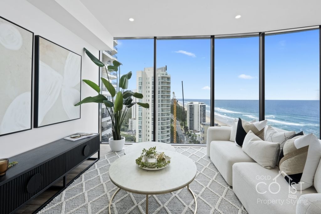A living room with a couch and a table with a view of the ocean