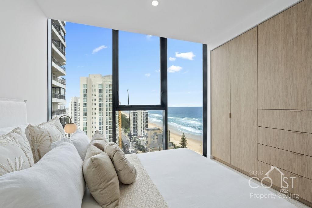 A bedroom with a large window overlooking the ocean.