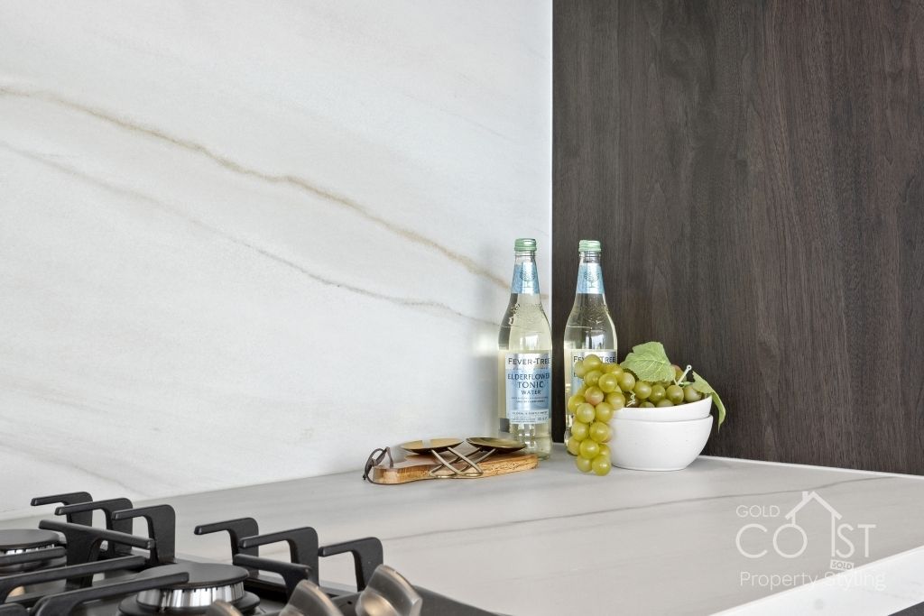 A kitchen counter with a stove , bottles of water , grapes and a bowl of grapes.