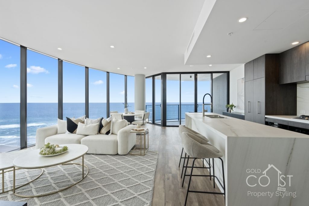 A living room with a couch and a table and a view of the ocean.