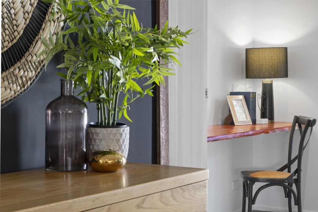 A plant is sitting on top of a wooden table next to a chair.