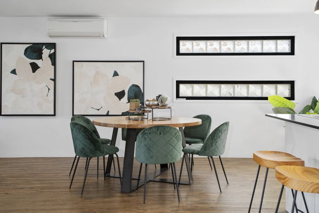 A dining room with a table and chairs and paintings on the wall.