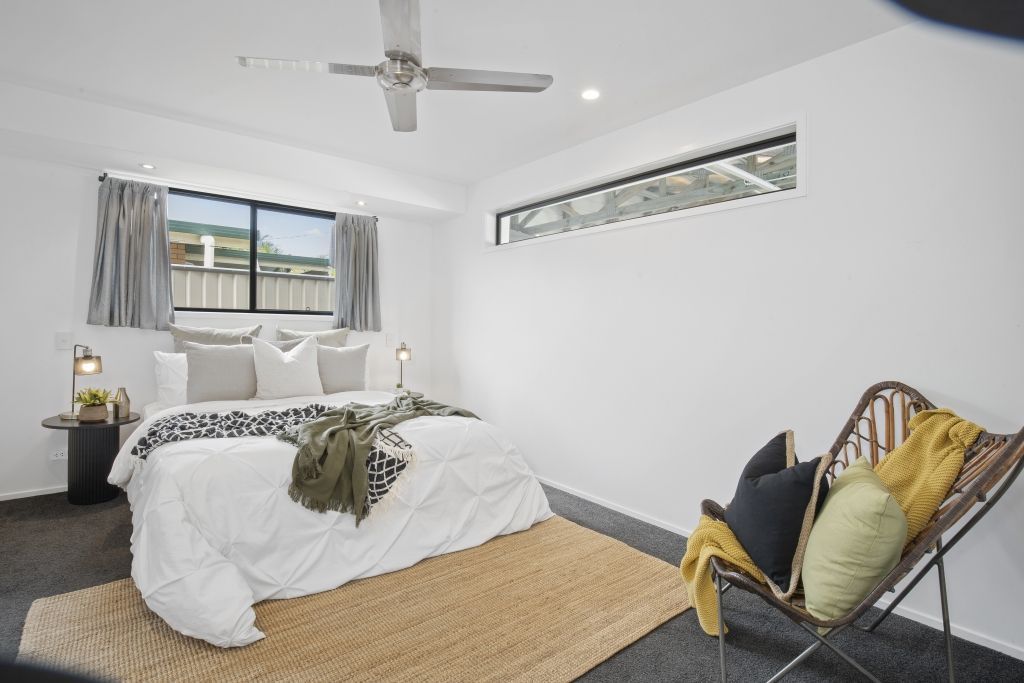 A bedroom with a bed , chair , rug and ceiling fan.