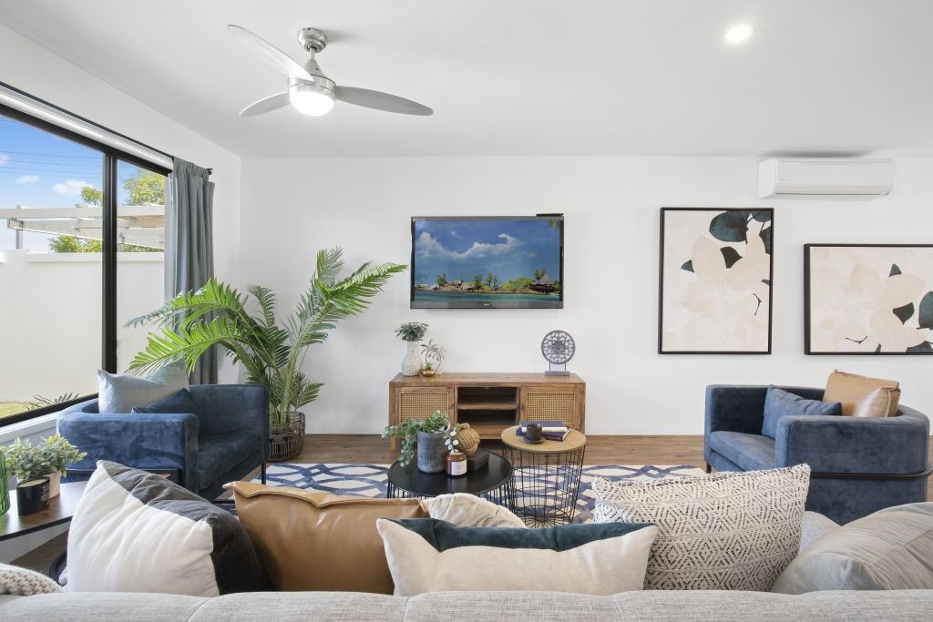 A living room with a couch , chairs , and a ceiling fan.