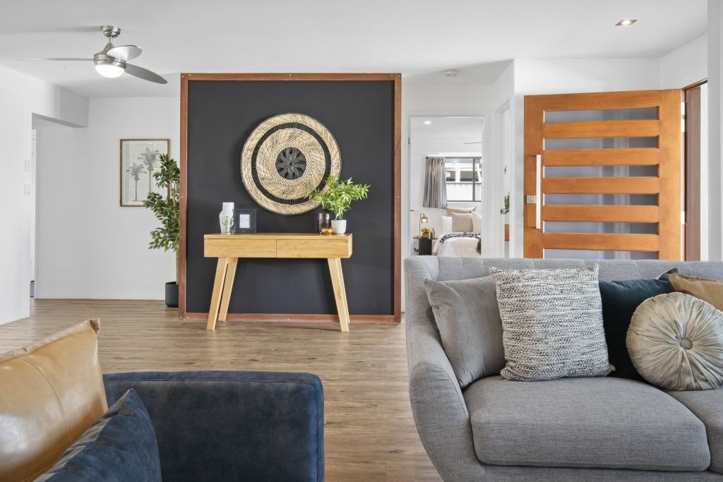 A living room with a couch , chair , table and ceiling fan