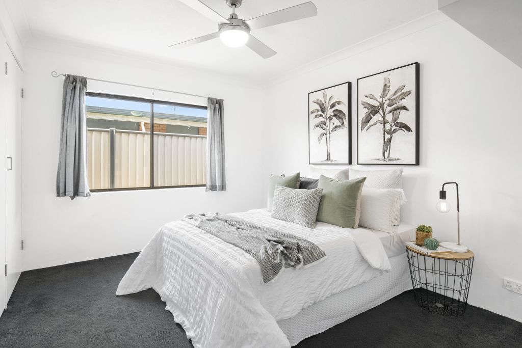 A bedroom with a bed and a ceiling fan