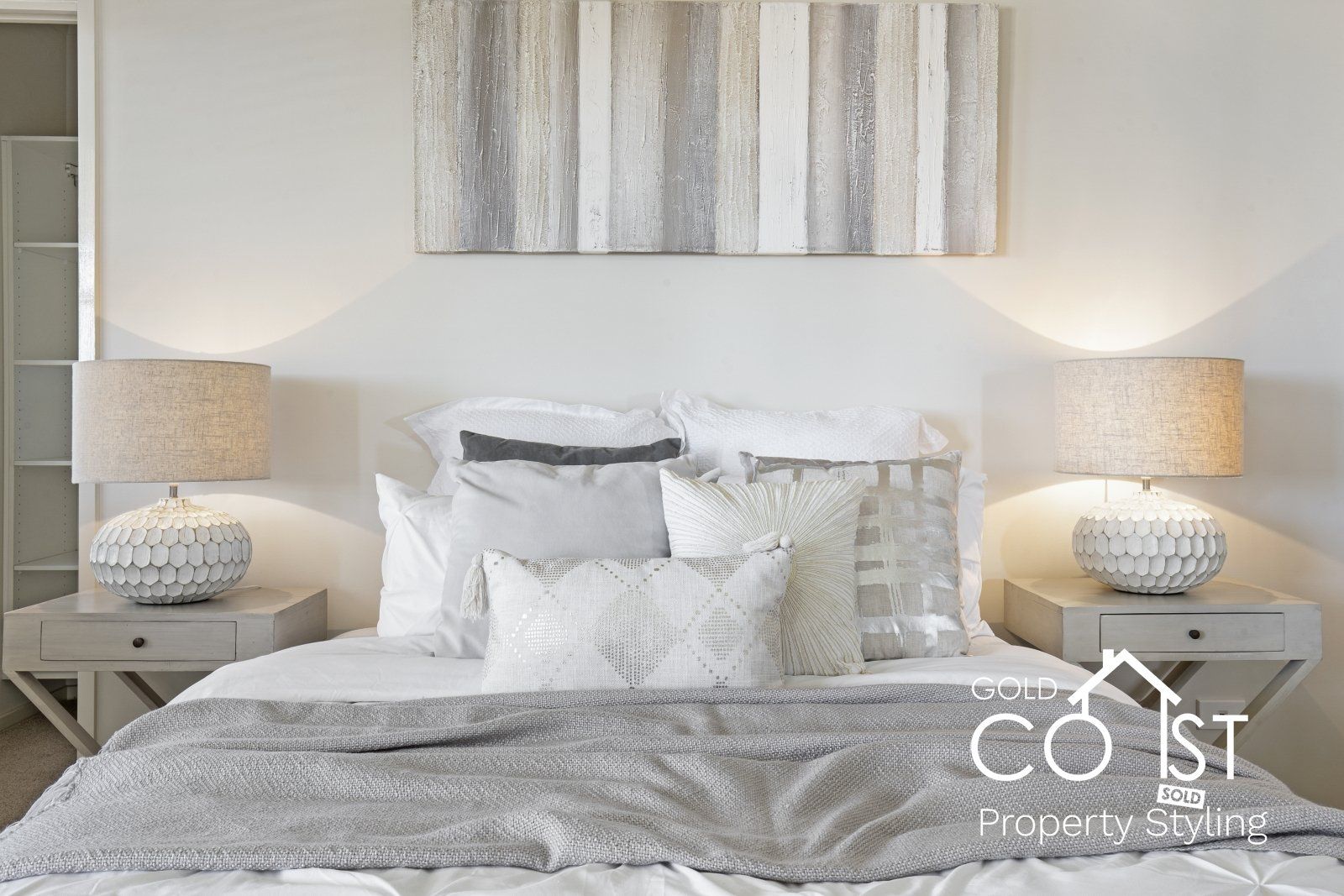 A bedroom with a bed , nightstands , lamps and a painting on the wall.