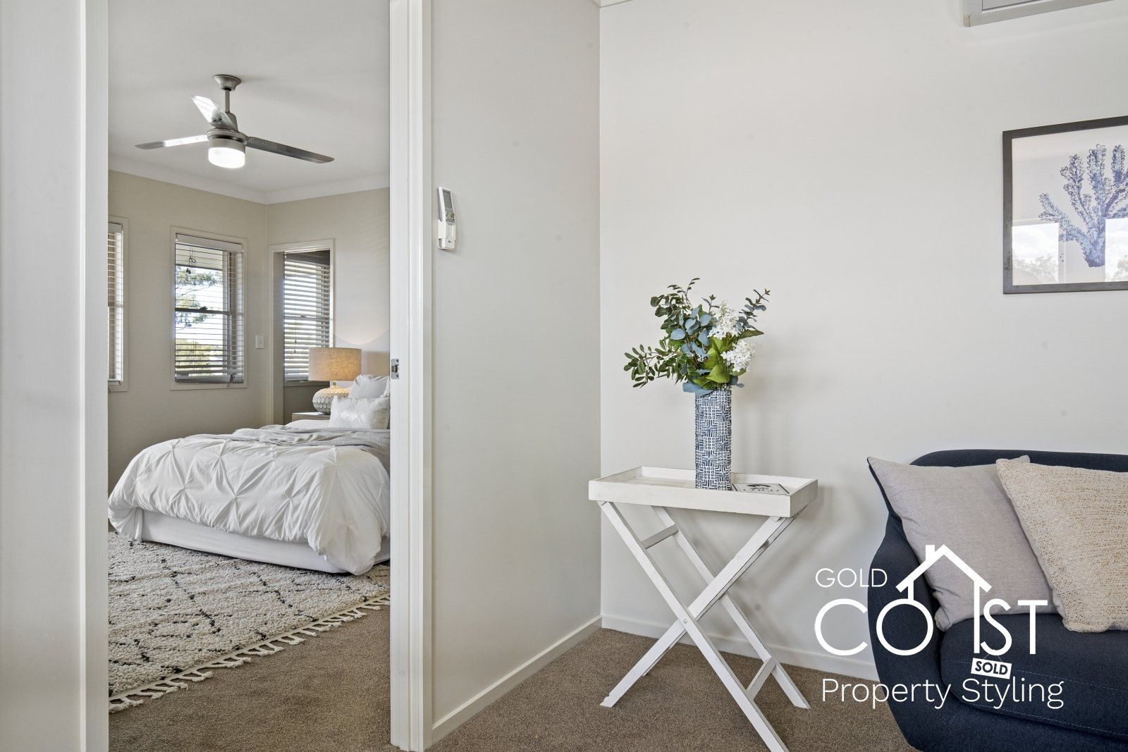 A bedroom with a bed , couch , table and ceiling fan.