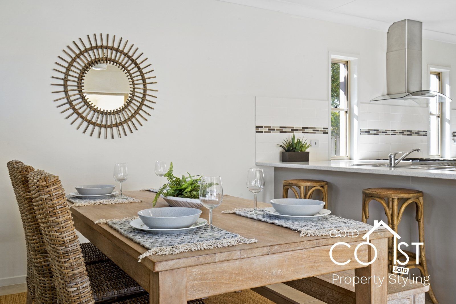 A dining room with a wooden table and chairs and a mirror on the wall.