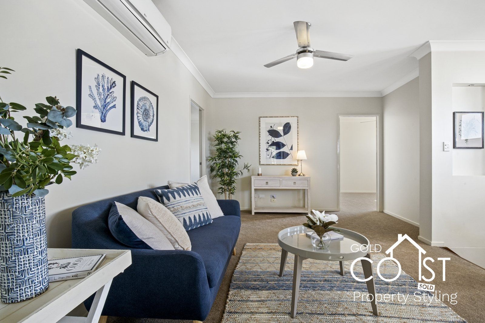 A living room with a blue couch and a ceiling fan.