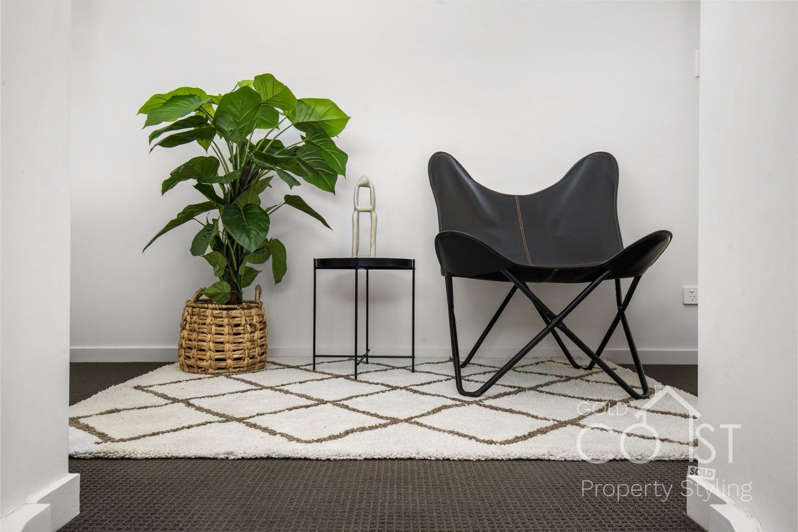 A black chair is sitting on a rug next to a plant