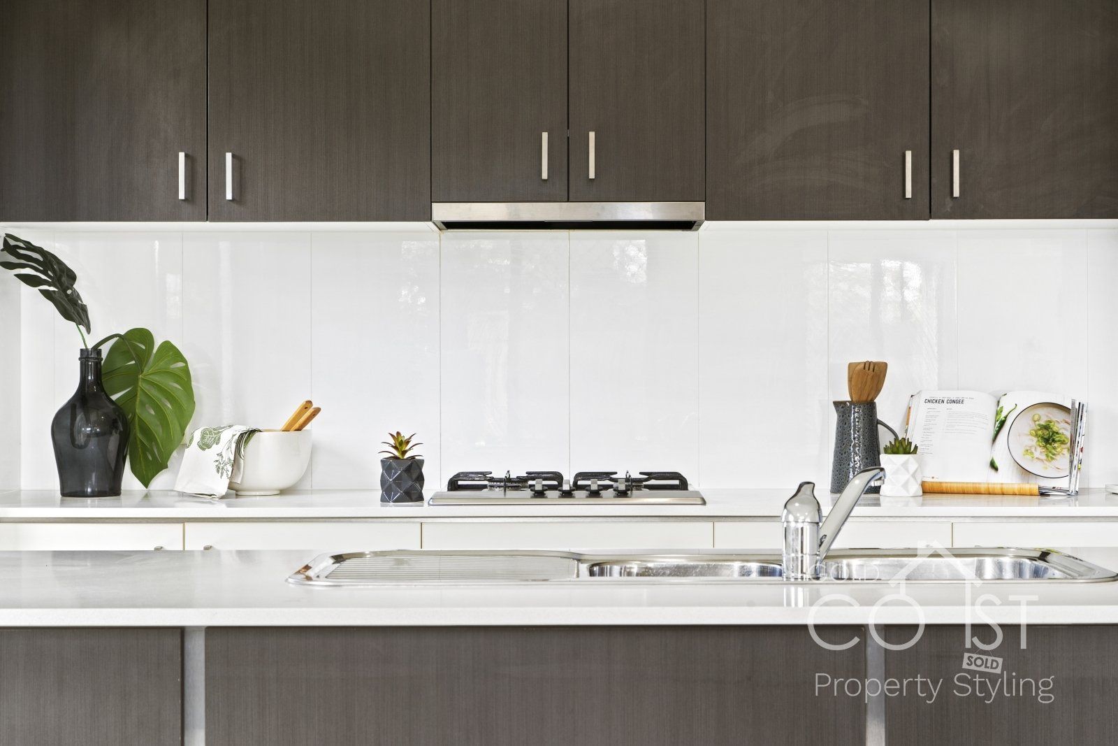 A kitchen with a stove top oven , sink , and cabinets.