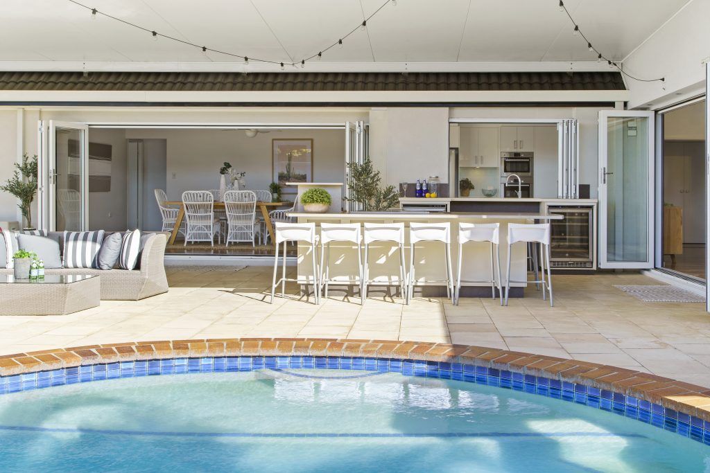 There is a large swimming pool in the backyard of a house.