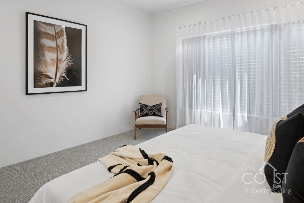 A bedroom with a bed , chair and a picture on the wall.