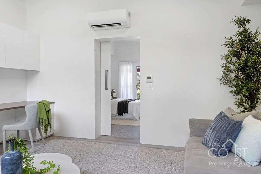 A living room with a couch , table , chair and air conditioner.