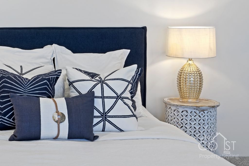 A bed with blue and white pillows and a lamp