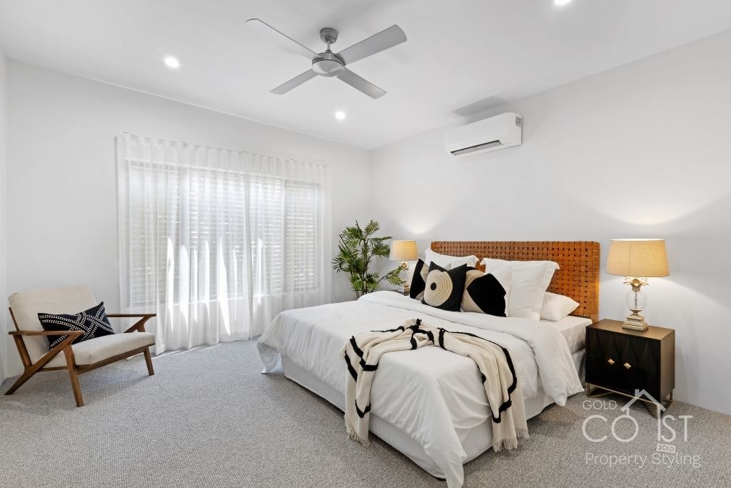 A bedroom with a bed , chair , nightstand and ceiling fan.