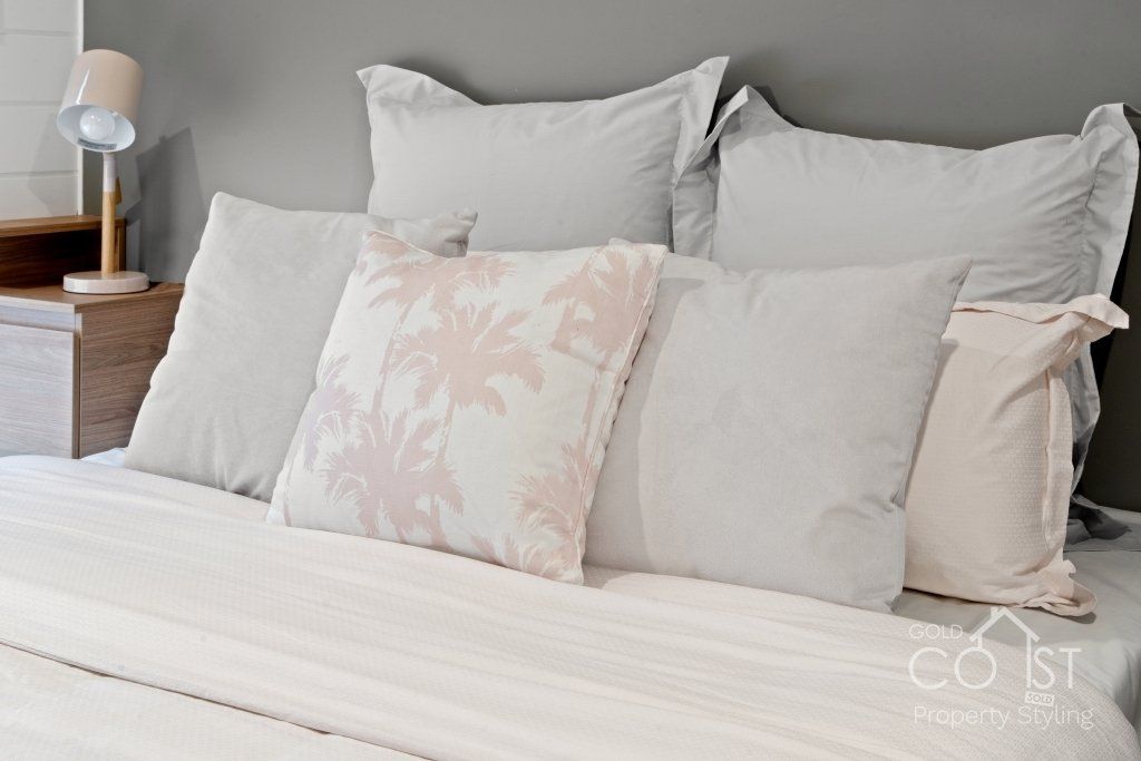 A bed with white sheets and pillows in a bedroom.