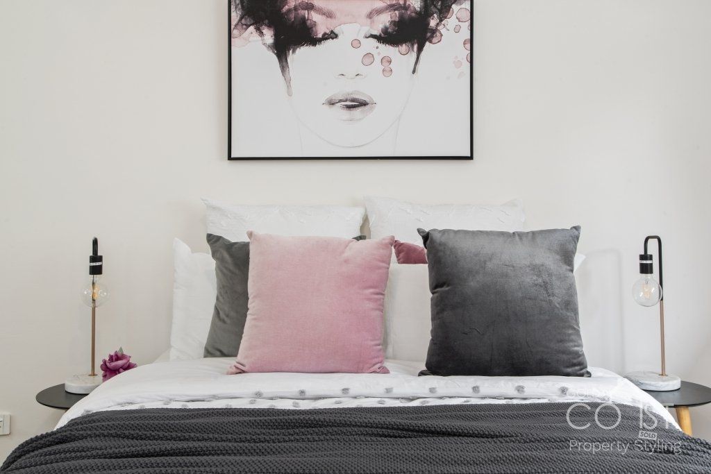 A bedroom with a bed , pillows and a painting on the wall.