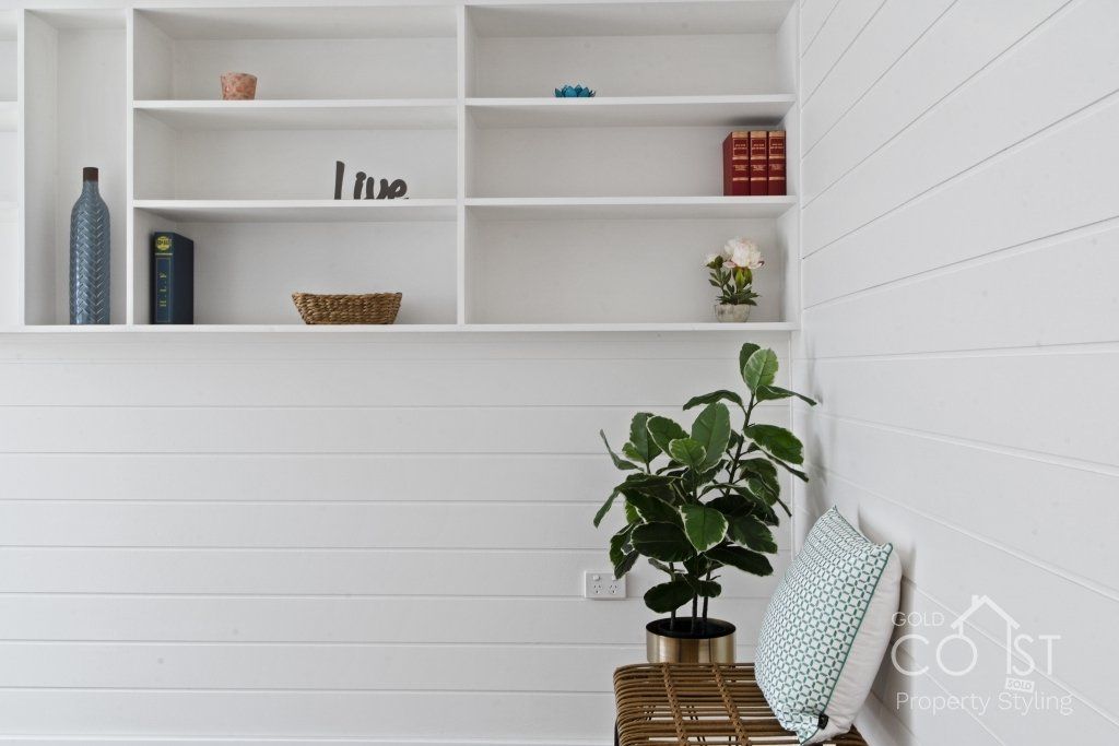 A white wall with shelves and a potted plant