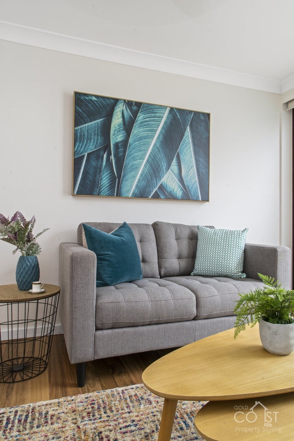 A living room with a couch , coffee table , and a painting on the wall.