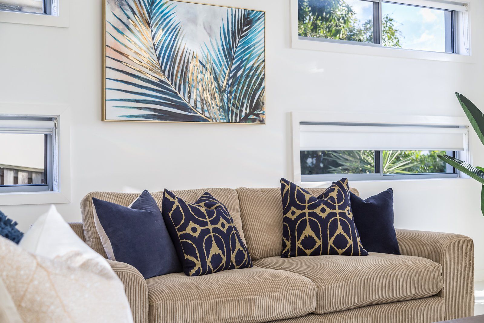 A living room with a couch , pillows and a painting on the wall.