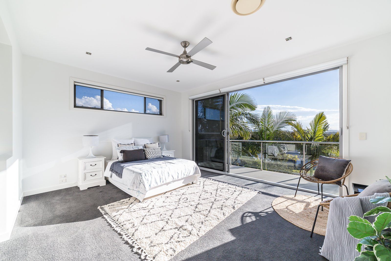 A bedroom with a bed , chair , rug and ceiling fan.
