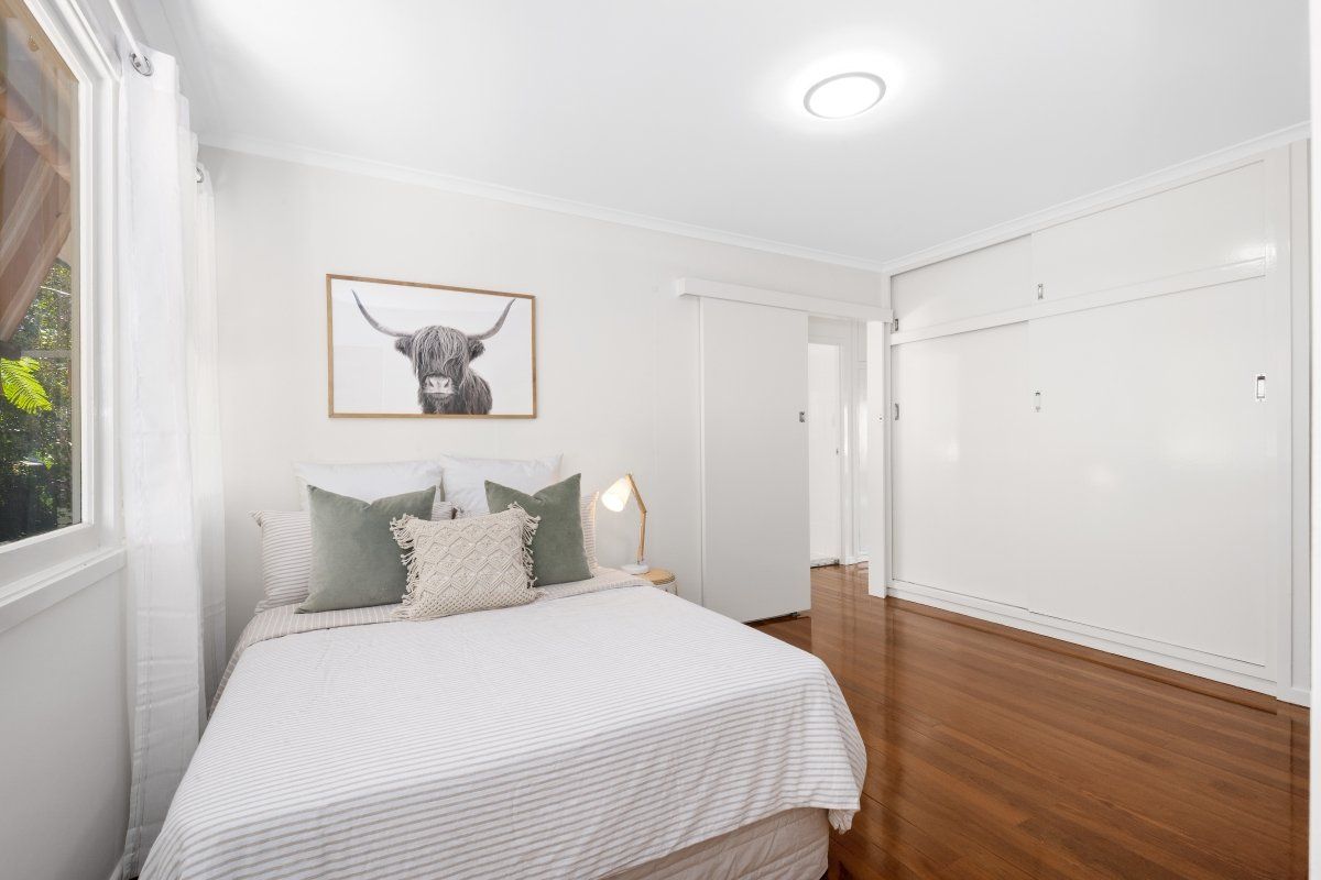 A bedroom with a bed and a picture of a cow on the wall.