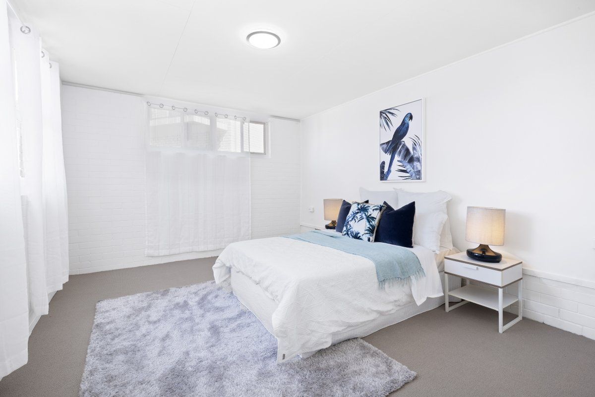 A bedroom with a bed , nightstand , and rug.