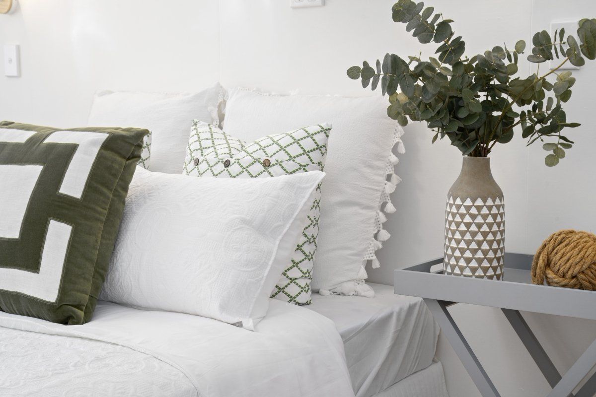 A bed with white sheets and green and white pillows