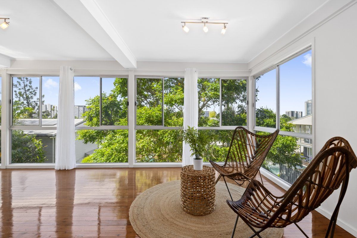 A living room with a lot of windows and chairs