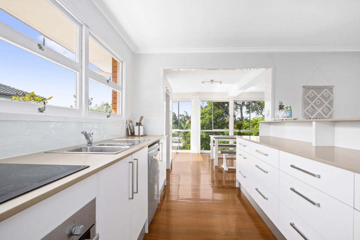 A kitchen with white cabinets , a sink , and a stove.