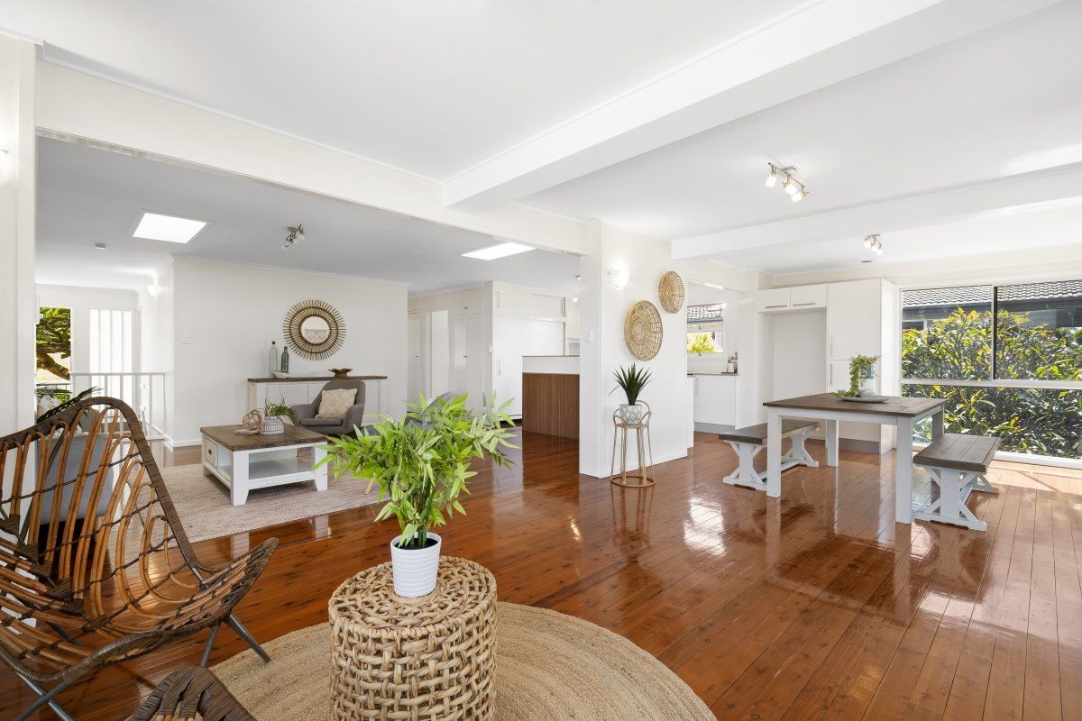 A living room with hardwood floors , wicker furniture , a table and chairs.
