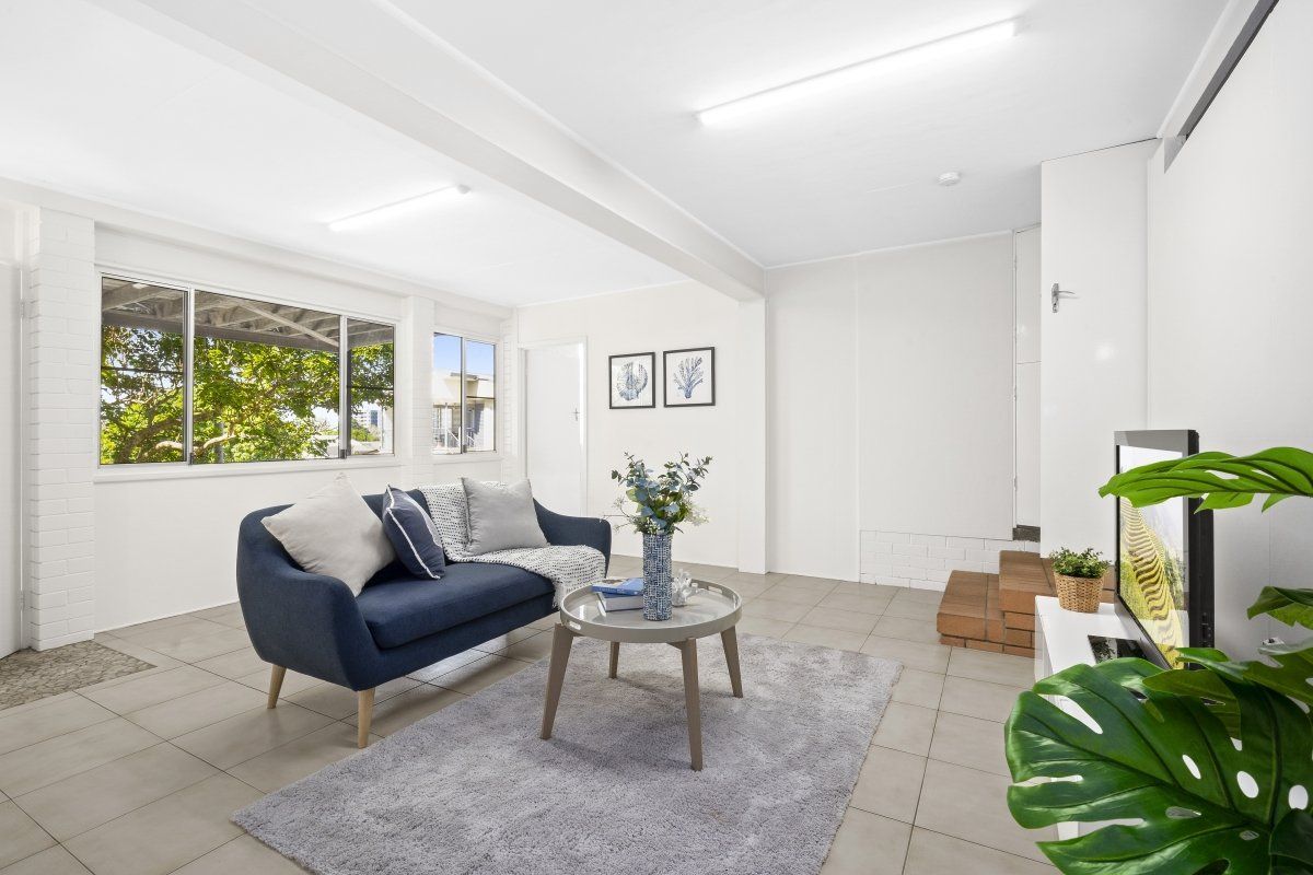 A living room with a couch , chair , table and television.