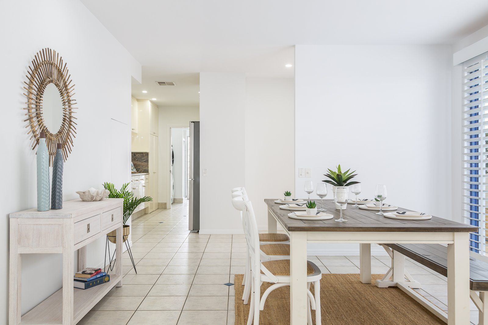 A dining room with a table and chairs and a mirror.