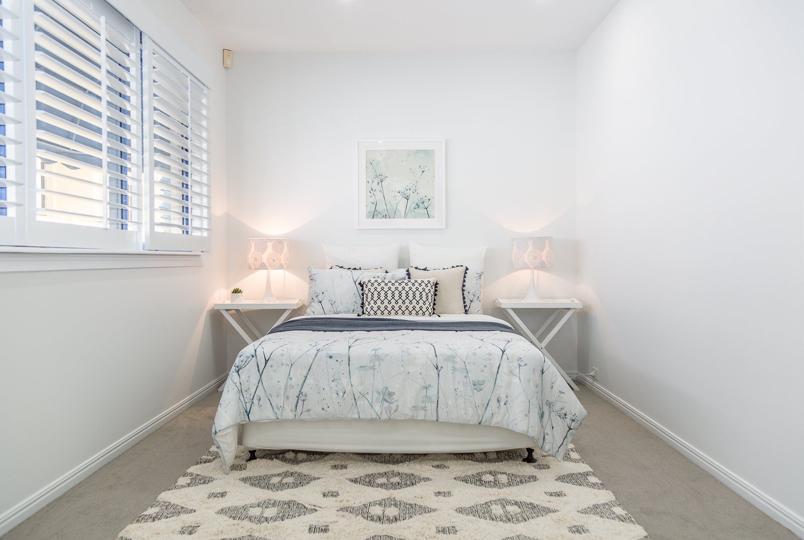 A bedroom with a bed , nightstands , and a rug.