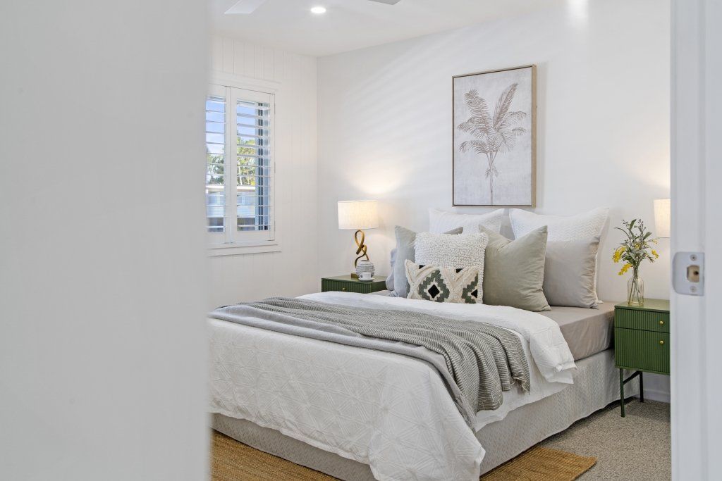 A bedroom with a large bed , nightstands , lamps and a window.