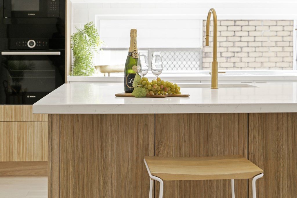 A kitchen with a bottle of champagne and grapes on the counter.