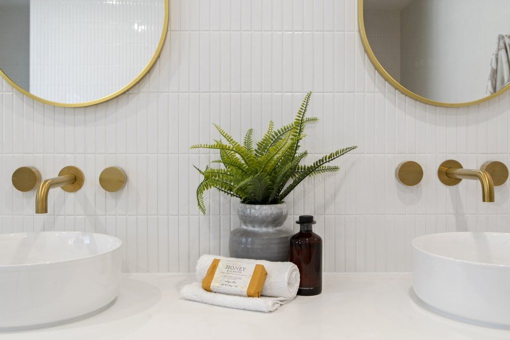 A bathroom with two sinks , two mirrors and a plant.