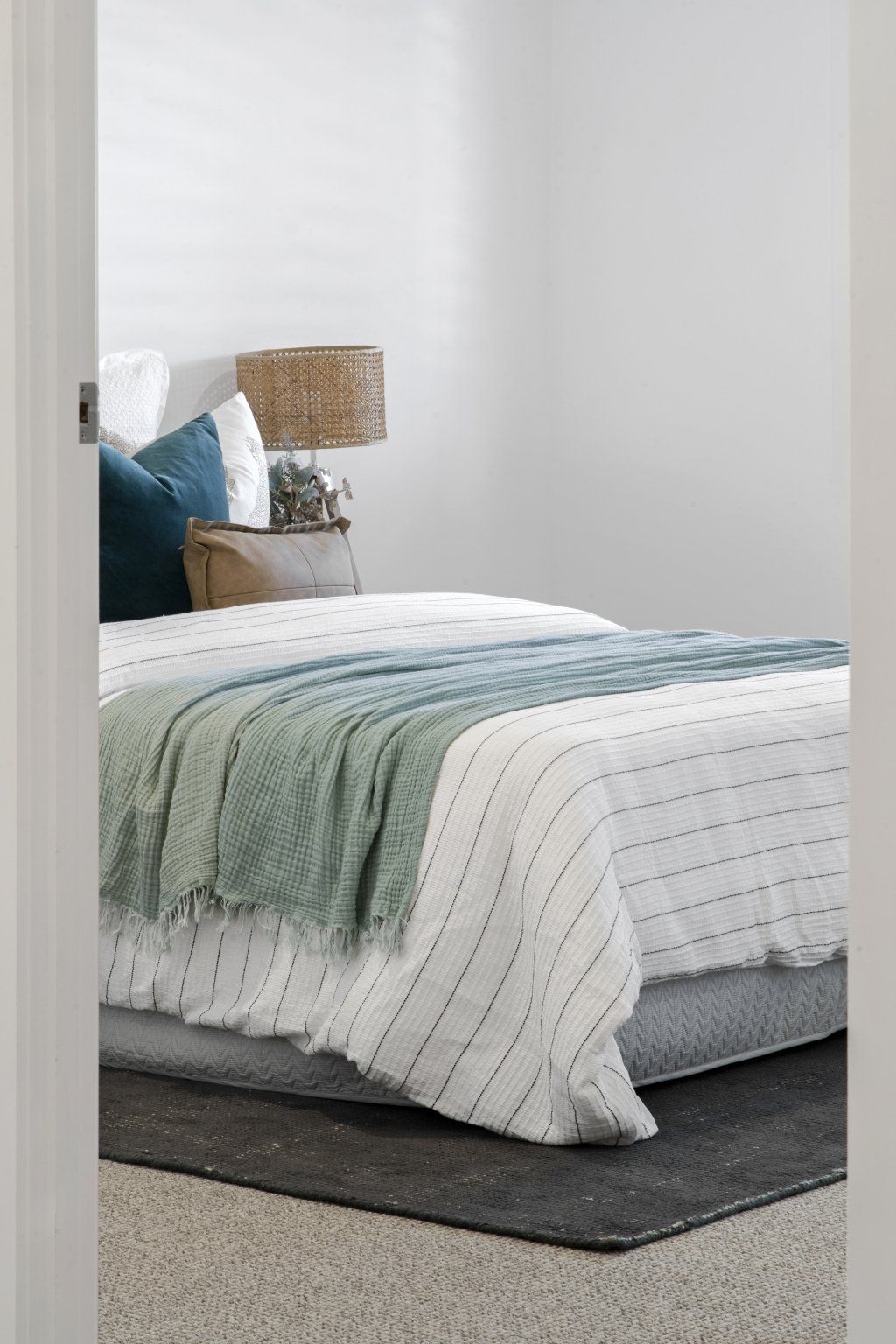 A bedroom with a bed , nightstand , lamp and rug.