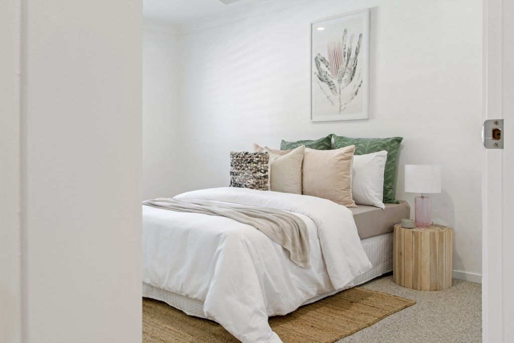 A bedroom with a bed , nightstand , lamp and rug.