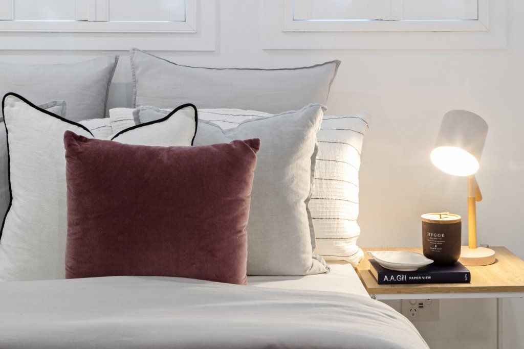 A bed with pillows and a lamp on a nightstand