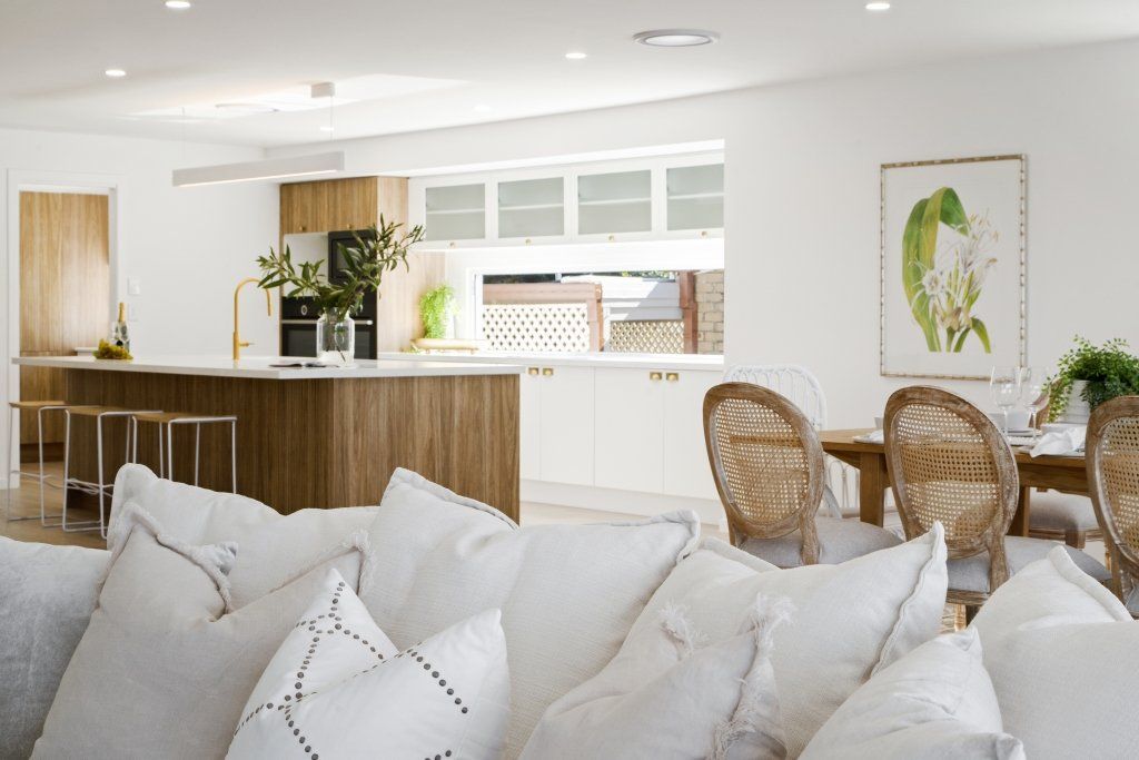 A living room with a couch and chairs and a kitchen in the background.