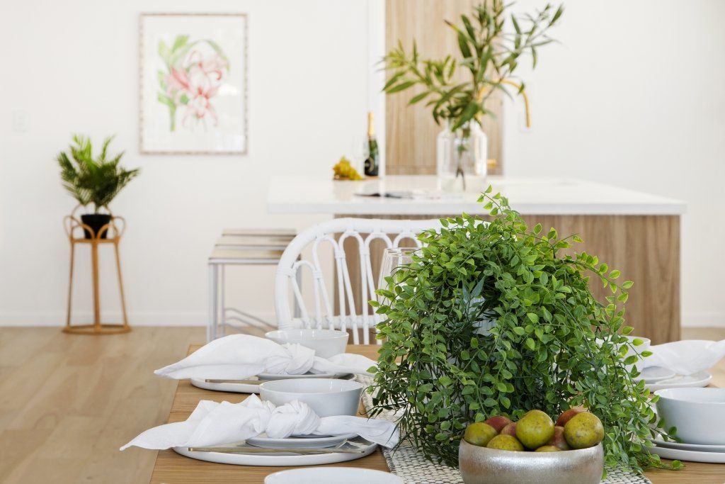 A dining room table with plates , bowls , and a plant on it.