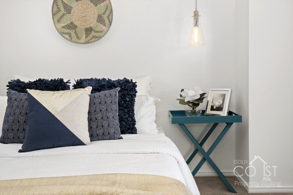 A bedroom with a bed , nightstand and a picture on the wall.